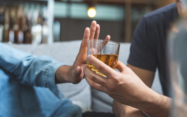 Persona rechazando bebida porque le sienta mal el alcohol.